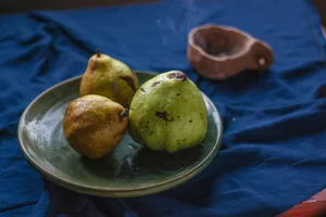 Overripe pears on a green plate set against a blue tablecloth, creating a rustic still life.