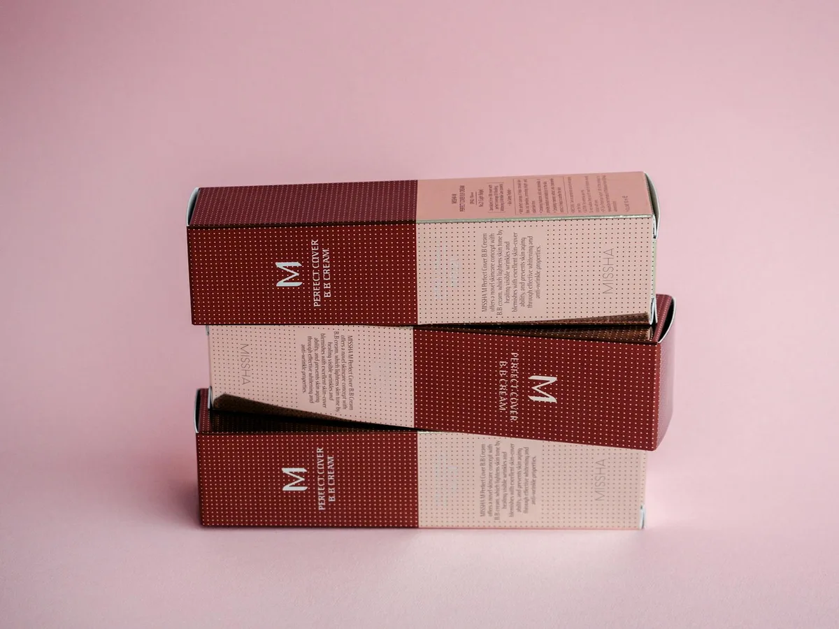 Exibição sofisticada de caixas de cosméticos luxuosas sobre fundo rosa pastel.