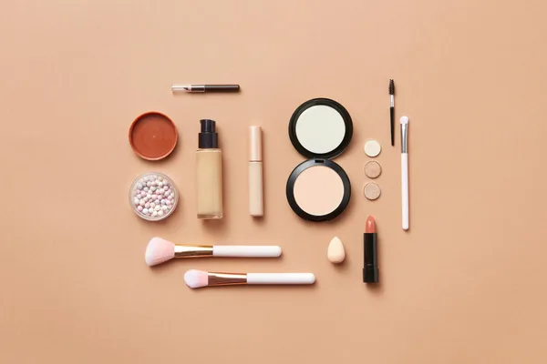 Stilvolles Flatlay verschiedener Make-up-Produkte auf weichem Pfirsichhintergrund
