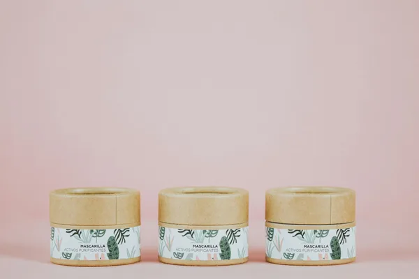 ピンク背景に植物柄のエコスキンケア瓶3点、サステナブルパッケージ