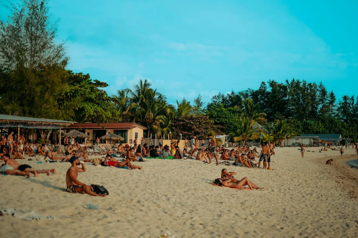 Vacanciers profitant d'une journée ensoleillée sur une plage tropicale avec palmiers et ciel bleu