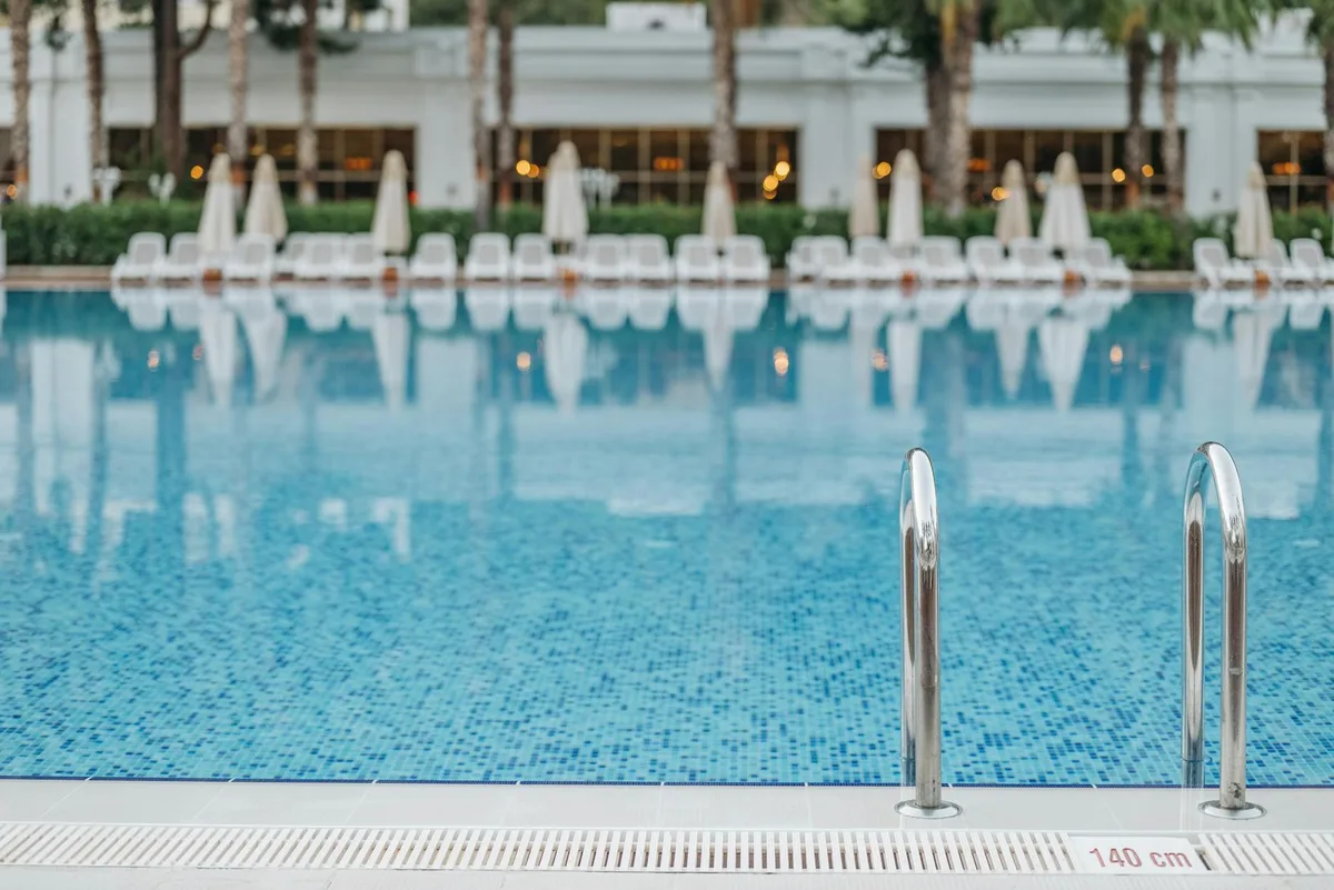 Heller und ruhiger Resort-Poolblick mit Leiter und Liegestühlen