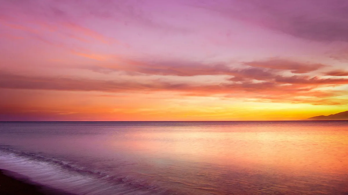 Faszinierender Sonnenuntergang mit warmen Farben über ruhigem Meer