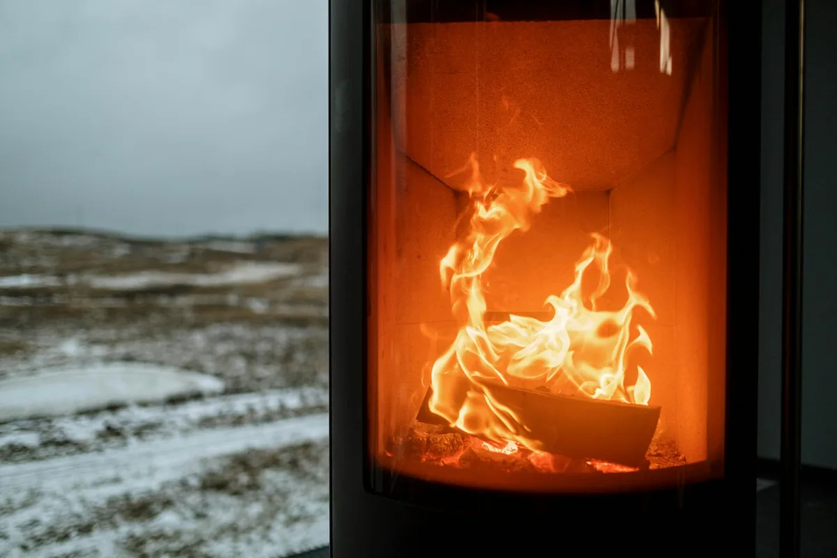 Kamin mit lodernder Flamme, der Wärme gegen den verschneiten Winter draußen spendet