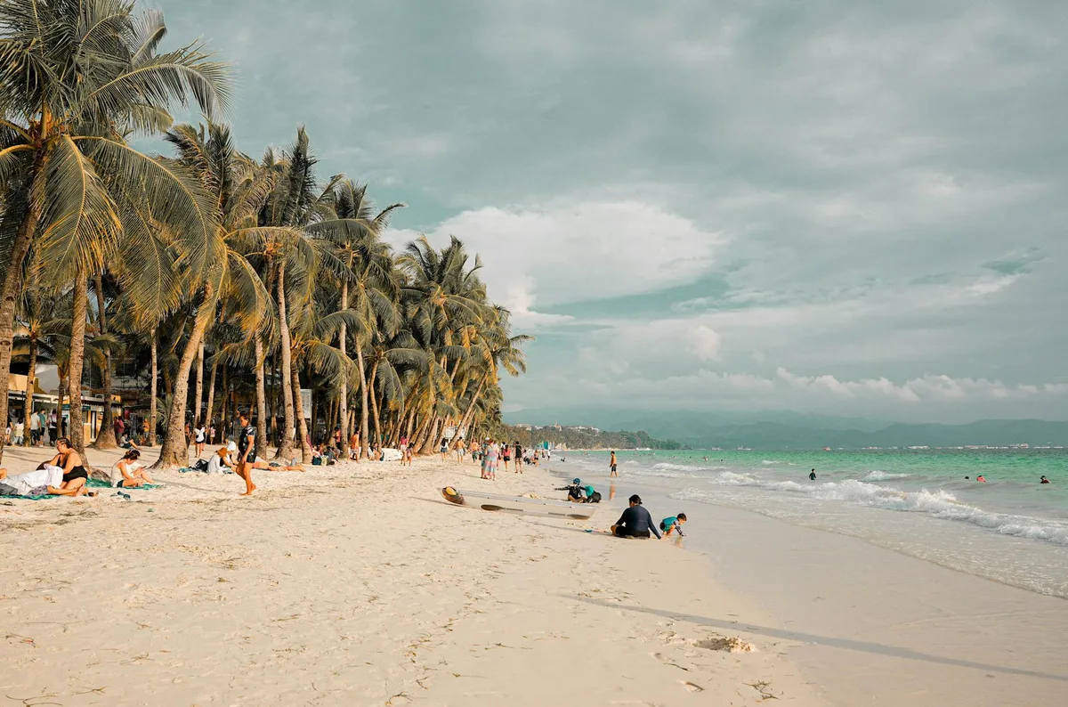 Tropischer Strand mit Palmen und Menschen, die Sand und Meer genießen