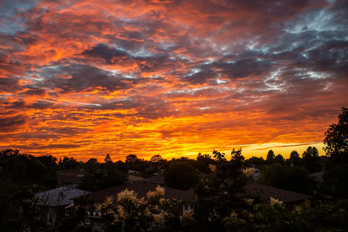 Sonnenuntergangshimmel mit dramatischen Wolken über Torontoer Vorstadtdächern