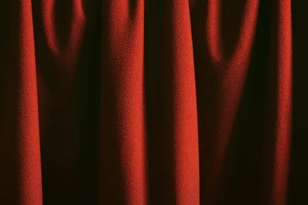 Classica tenda rossa con texture ricca e pieghe eleganti in luce soffusa.
