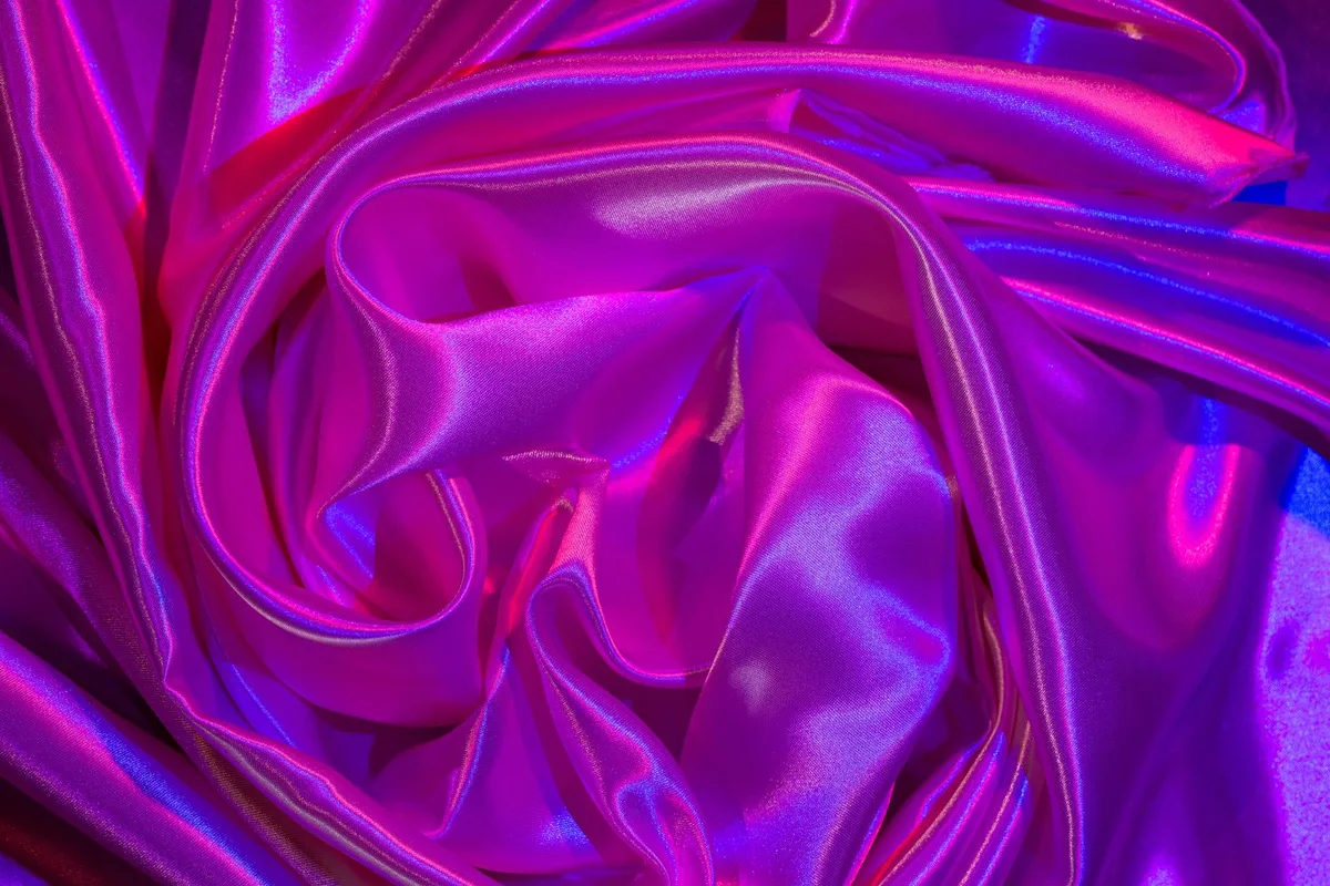 Tessuto raso viola e rosa con pieghe e texture lucida