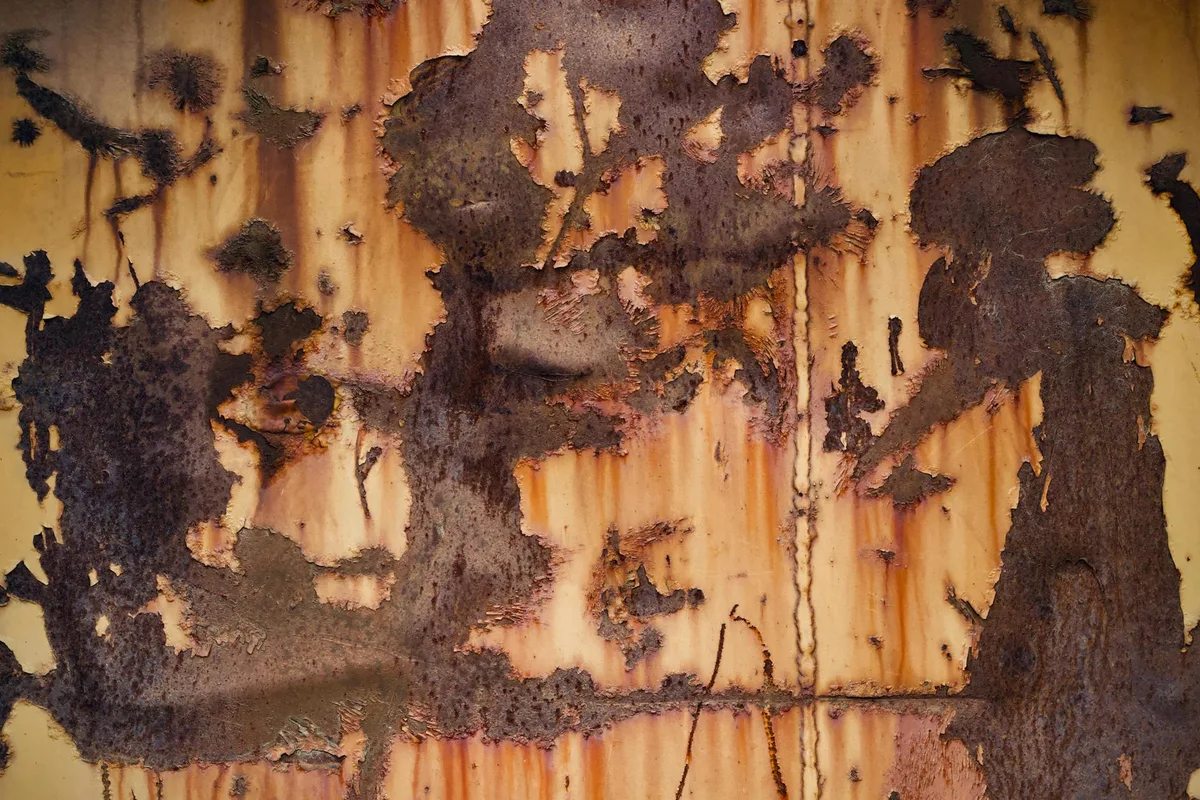 Primo piano di superficie metallica arrugginita con motivi astratti unici e texture.