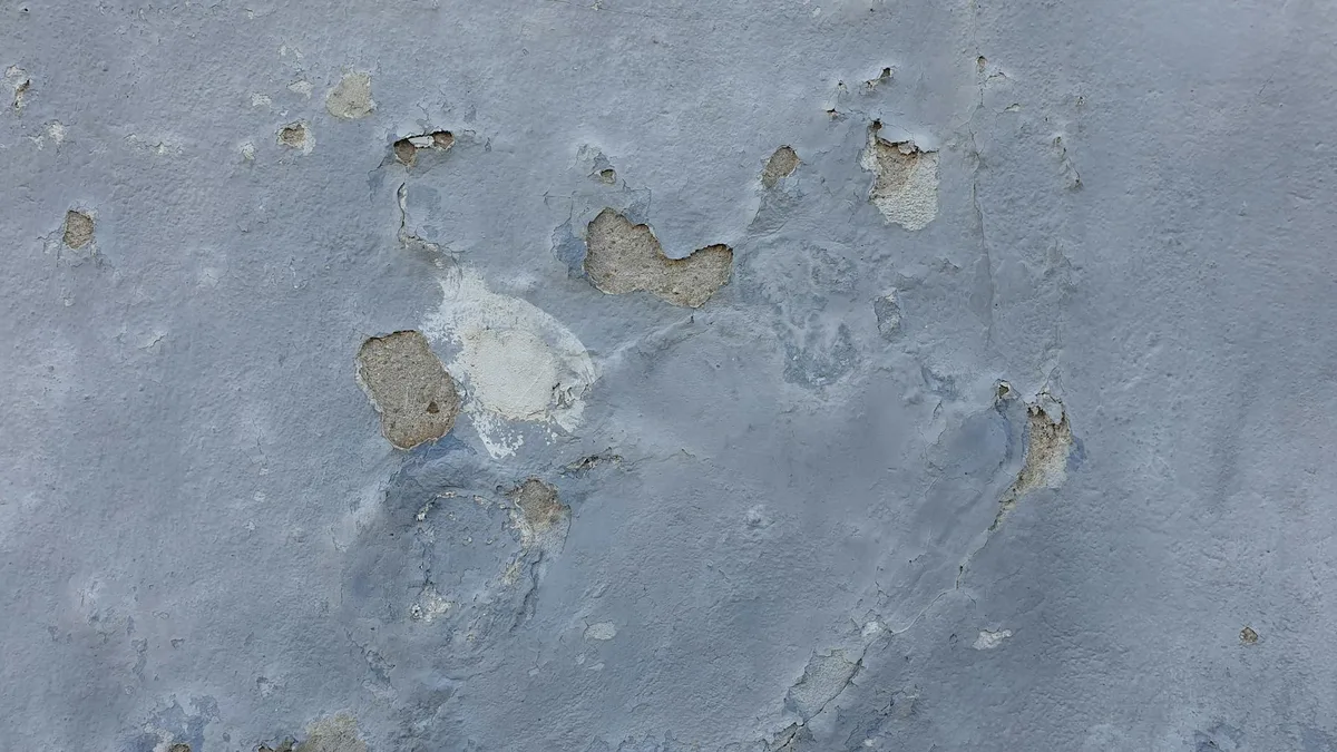 Primo piano muro cemento testurizzato con crepe e pittura scrostata
