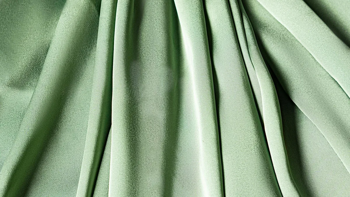 Primo piano di tessuto verde texturizzato e plissettato per moda e design
