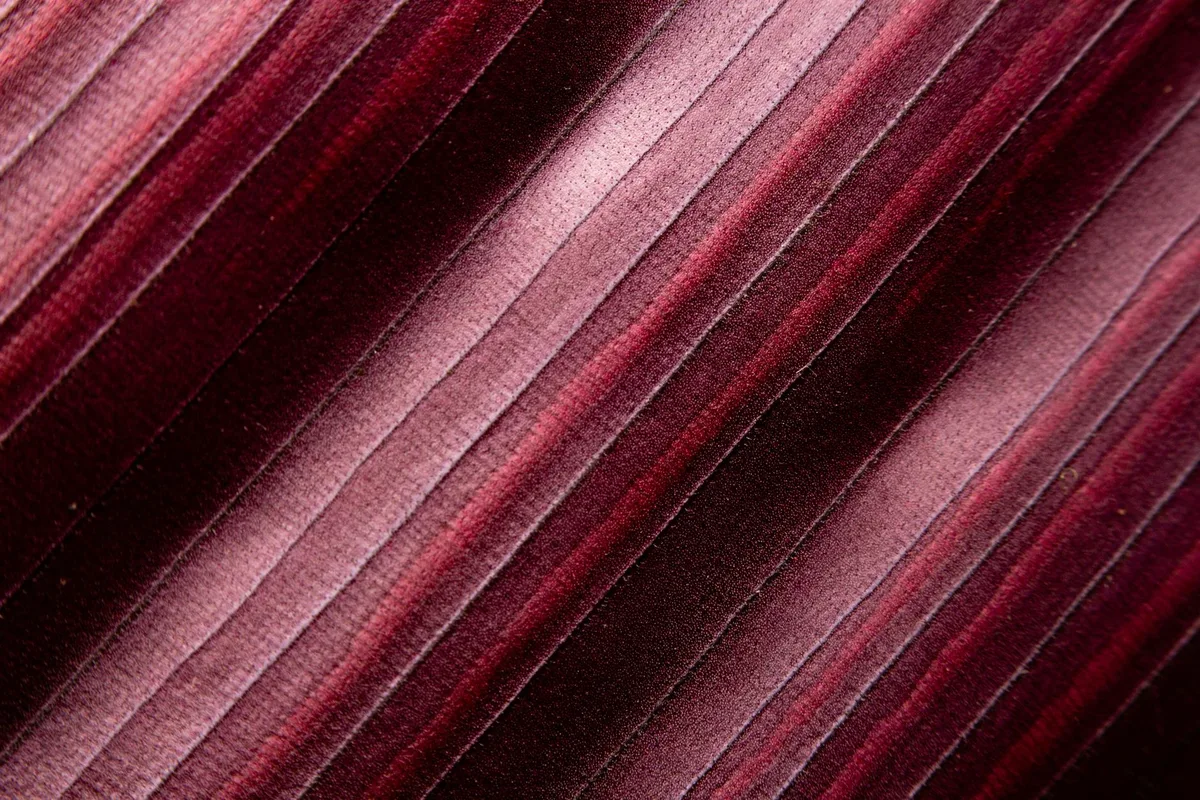 Nahaufnahme von weinrotem Stoff mit strukturiertem Streifenmuster für Textildesign