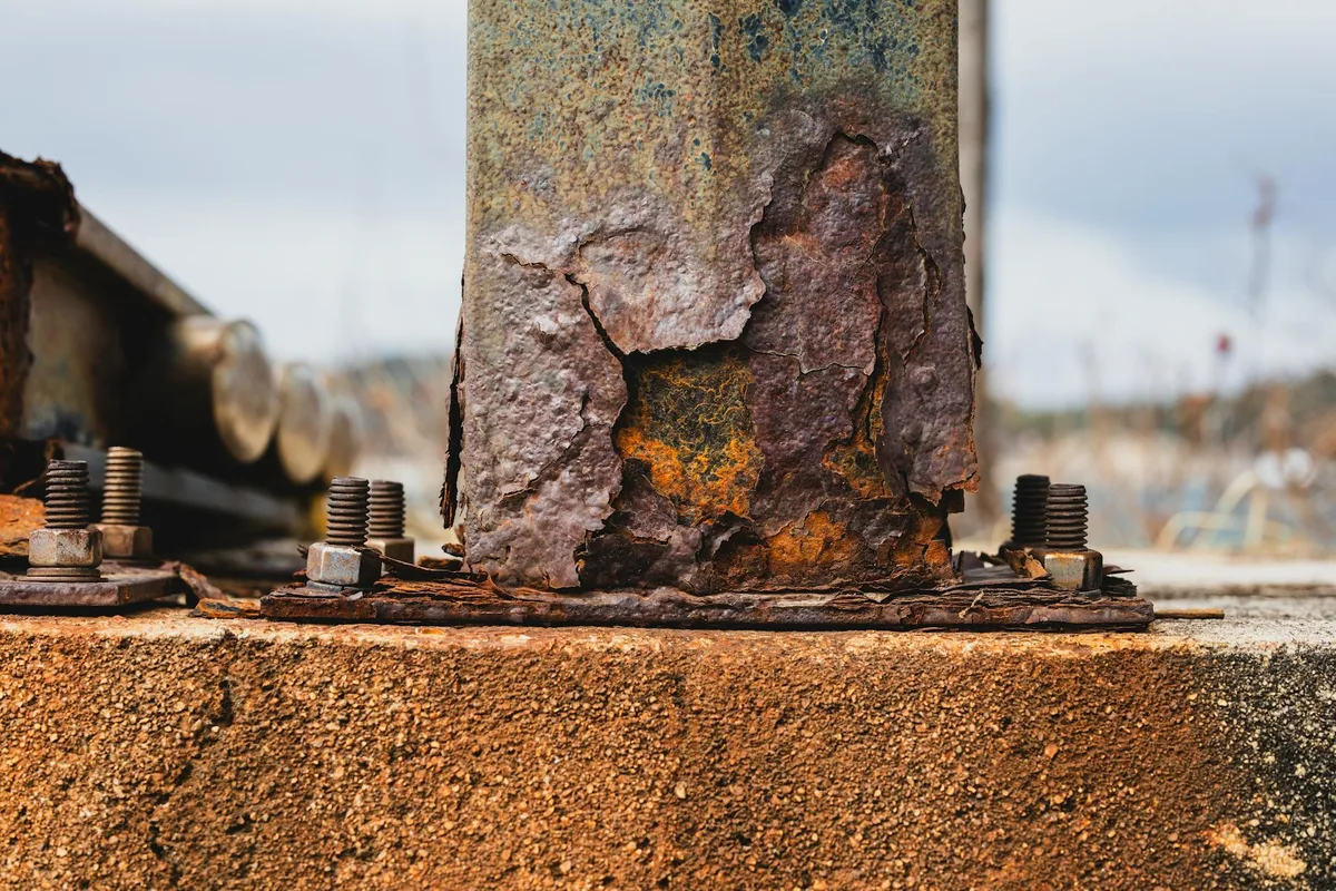 Detailed image of corroded metal with visible rust and bolts outdoors.
