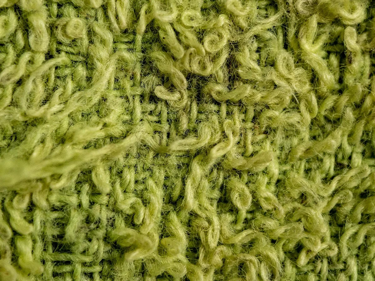 그린 니트 패브릭의 텍스처와 패턴을 보여주는 매크로 클로즈업