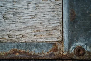 Detailed texture of rusty metal meeting aged wood, showcasing contrast.