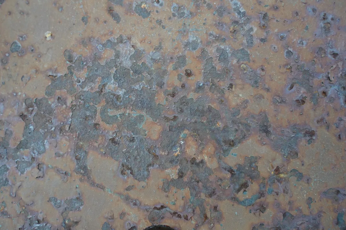 Primo piano di superficie metallica corrosa con texture e variazioni cromatiche