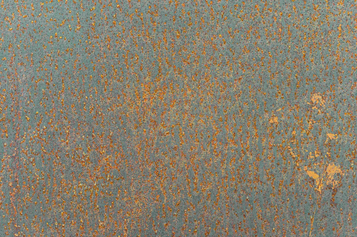 Detailansicht einer rostigen Metalloberfläche mit orangefarbener Patina und Erosion