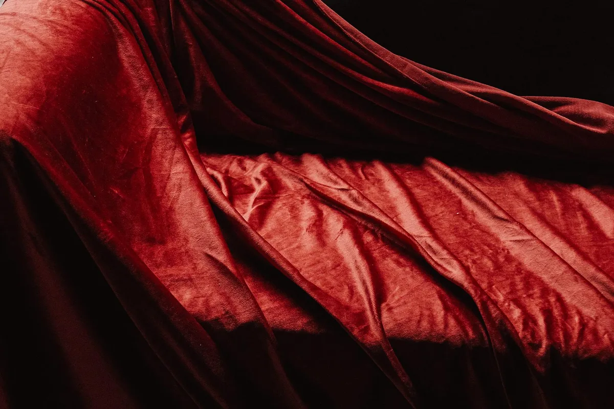 Ricca texture di velluto rosso lussuoso drappeggiato con ombre morbide e luci