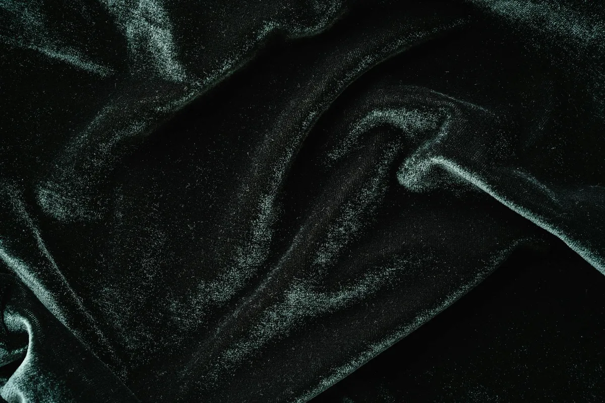 Velluto nero texture ricca in primo piano con pieghe morbide e lucentezza