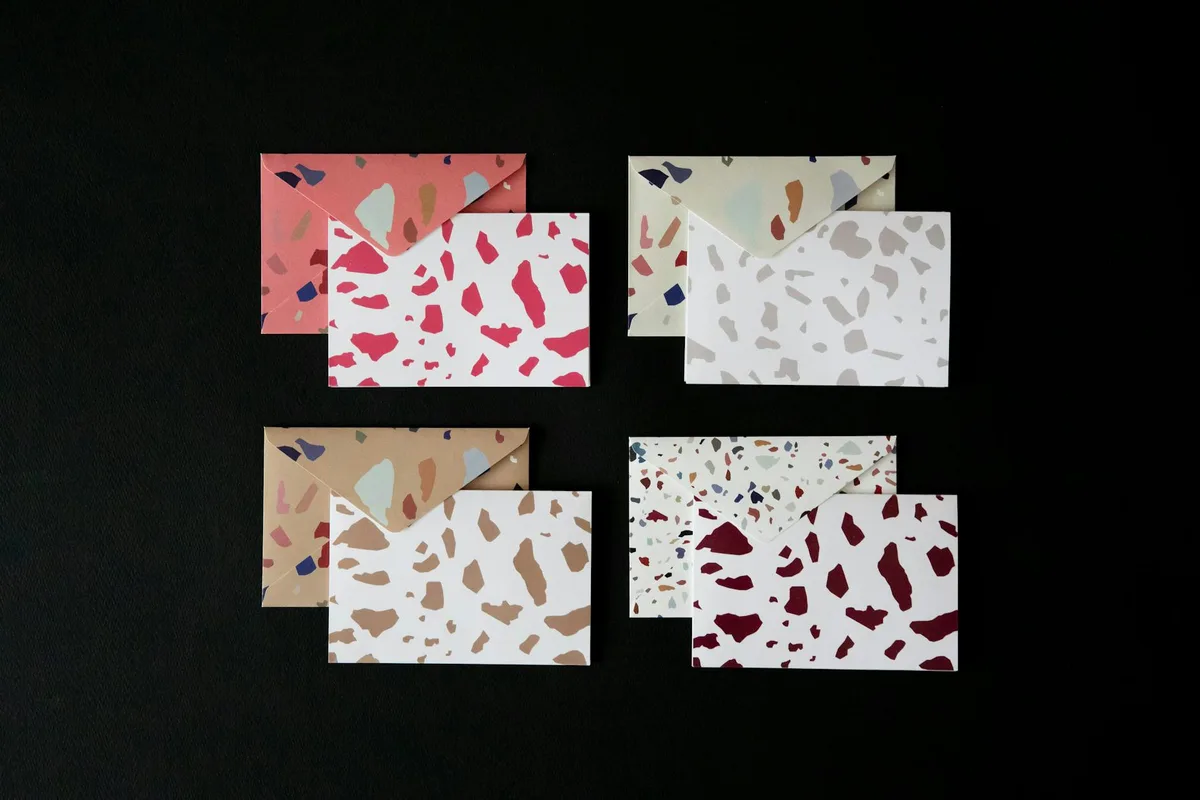 スタイリッシュなテラゾ柄の封筒セット、黒い表面に整然と配置。