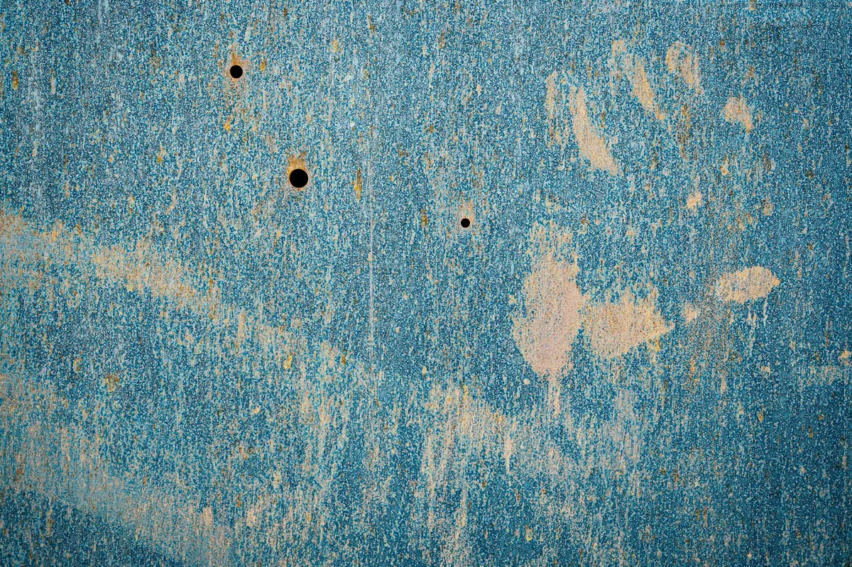 Parete metallica arrugginita con graffi su superficie blu