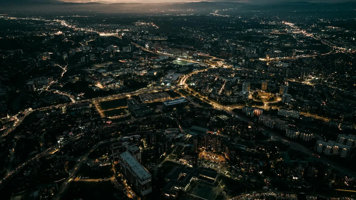 Vista aérea deslumbrante das luzes de Pristina iluminando a paisagem noturna
