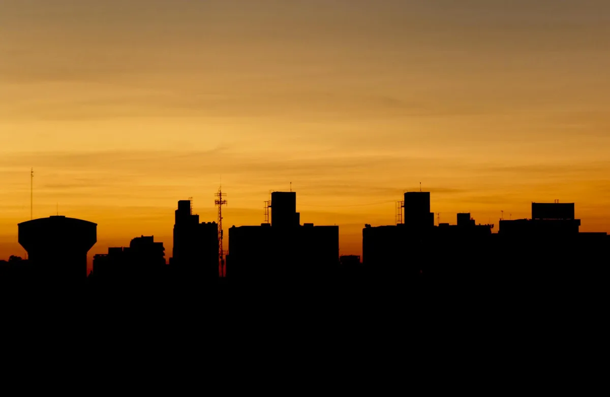 Dramatische Silhouette einer Stadtsilhouette vor einem lebendigen goldenen Sonnenuntergangshimmel