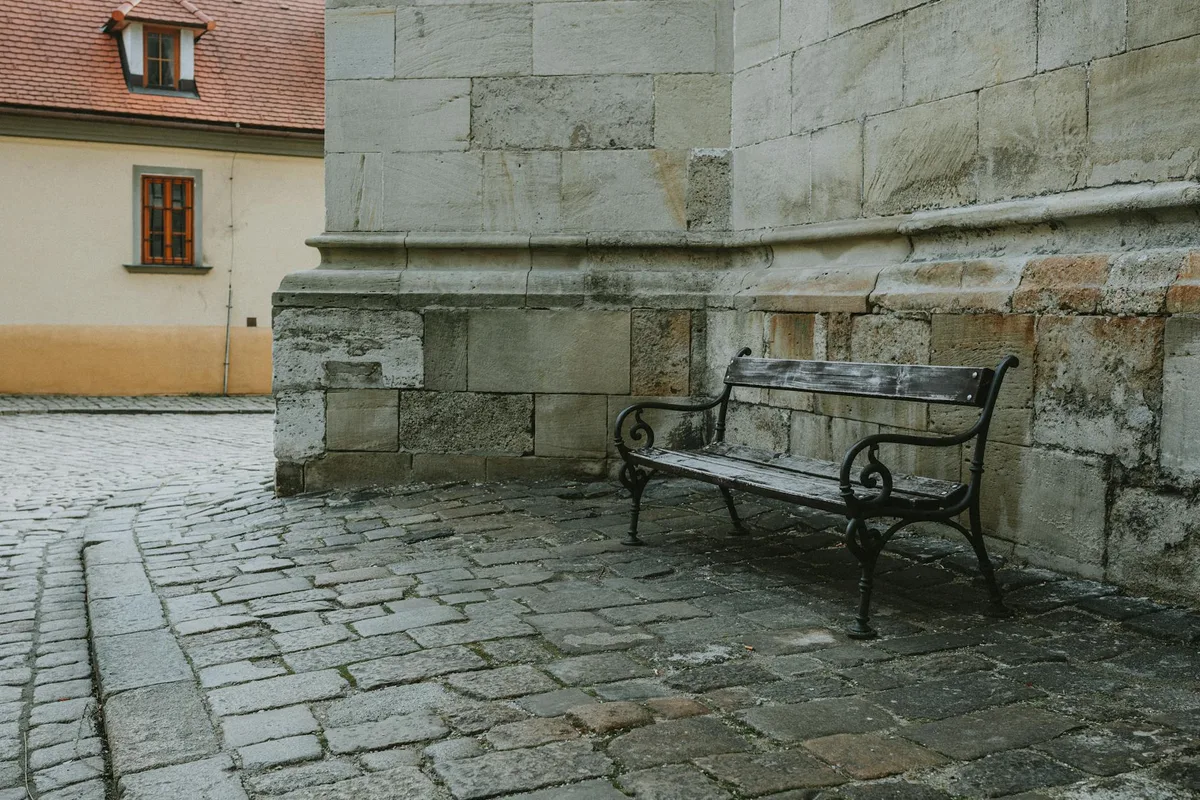 Ruhige Kopfsteinpflasterstraßenecke mit einer klassischen Holzbank in einer alten europäischen Stadt.
