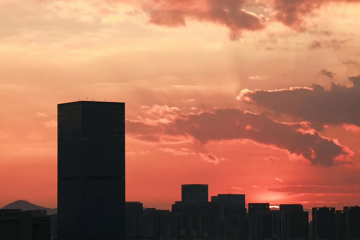 Skyline urbano al tramonto con grattacieli in silhouette e cielo vibrante