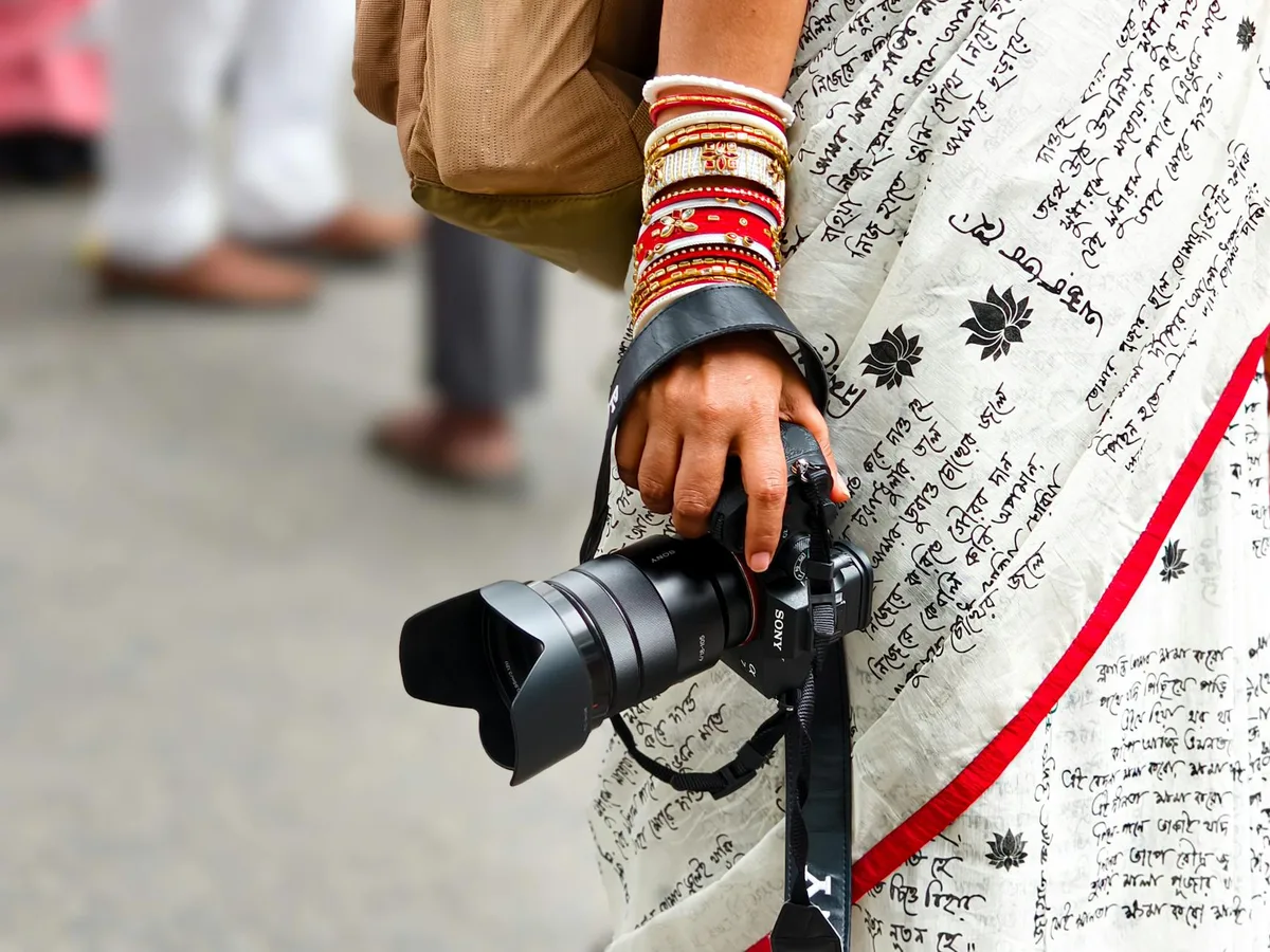 Femme en sari avec bracelets tenant un appareil photo