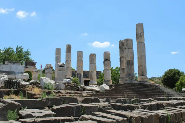 Sito archeologico antico con alte rovine colonnari sotto un cielo azzurro limpido.