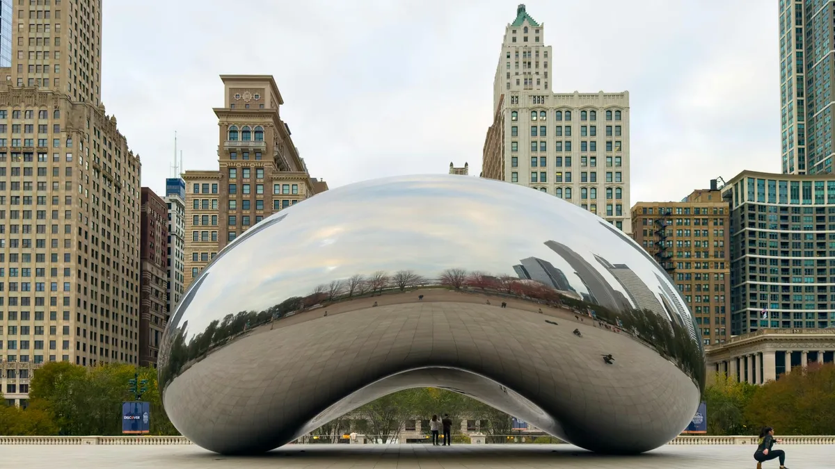 Escultura Cloud Gate de Chicago refletindo arranha-céus da cidade em um dia claro.
