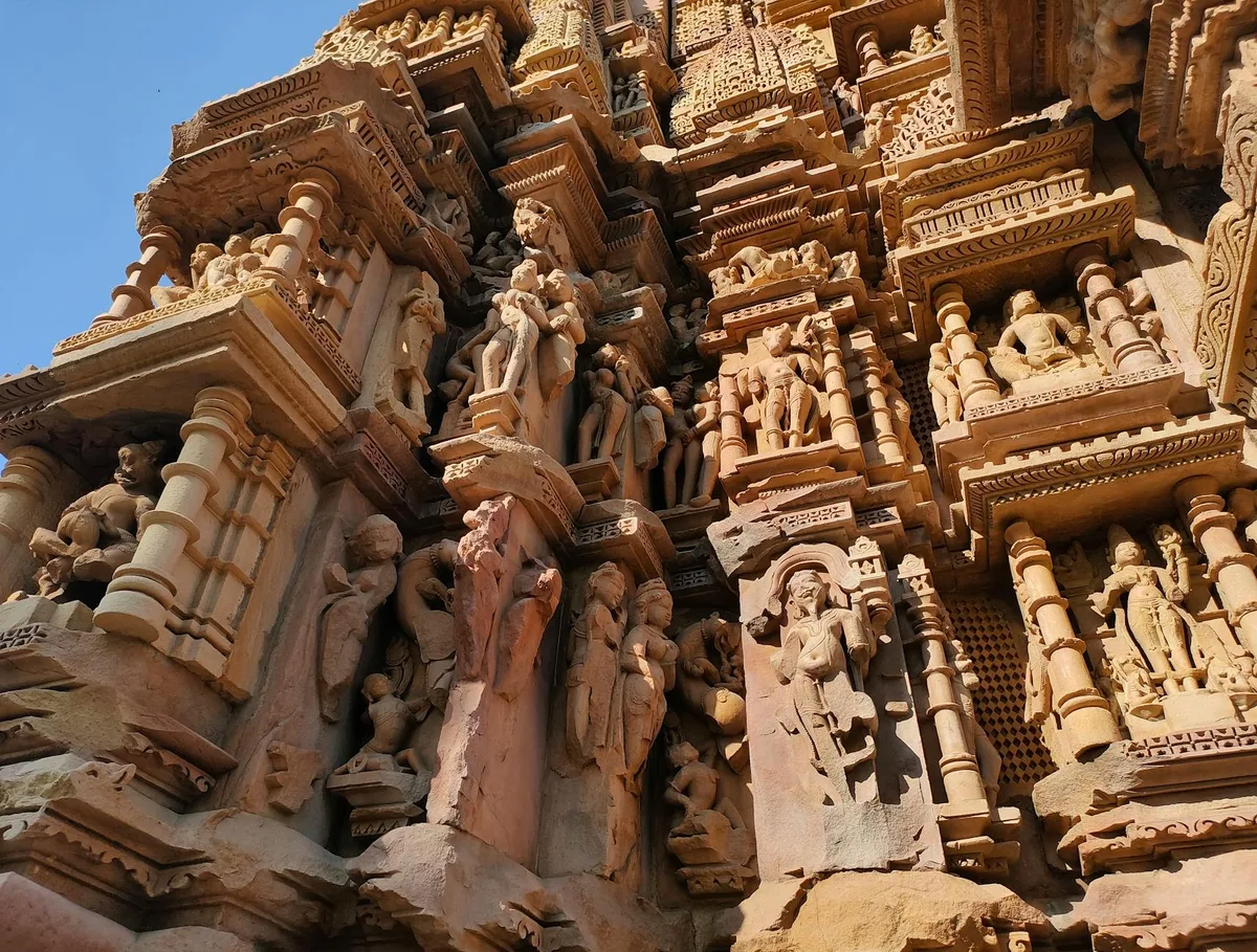 Esculturas detalhadas em pedra na fachada do templo em Khajuraho, Índia, exibindo arte indiana antiga.