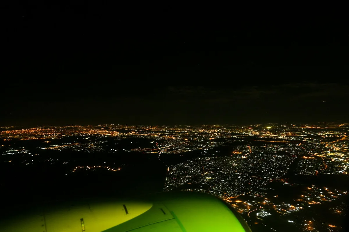 飛行機から見た夜の都市の劇的な航空写真。ブラックとオリーブの色調。