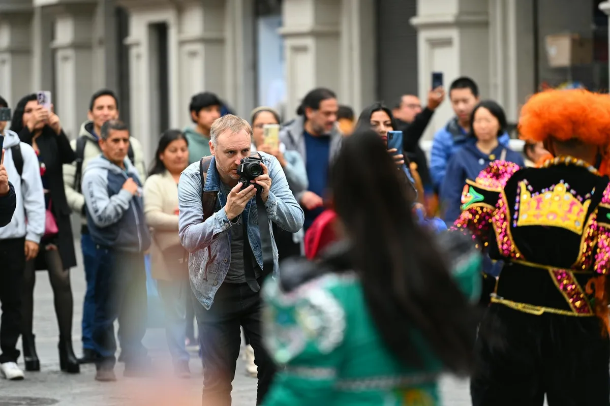 Scena dinamica di strada con fotografo che cattura una sfilata culturale vibrante tra la folla