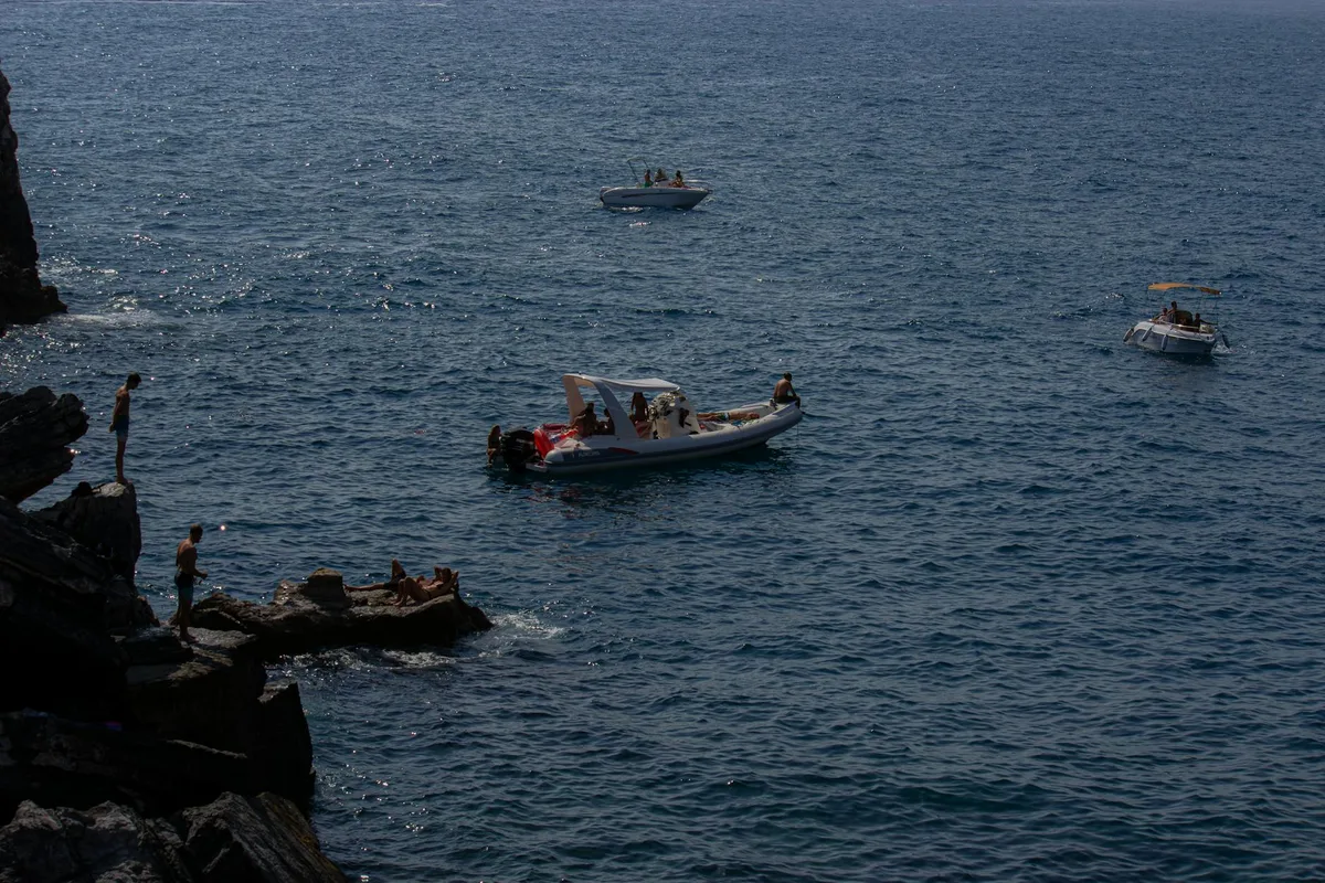 Día soleado con barcos y clavadistas en Porto Venere, la costa escénica de Italia.