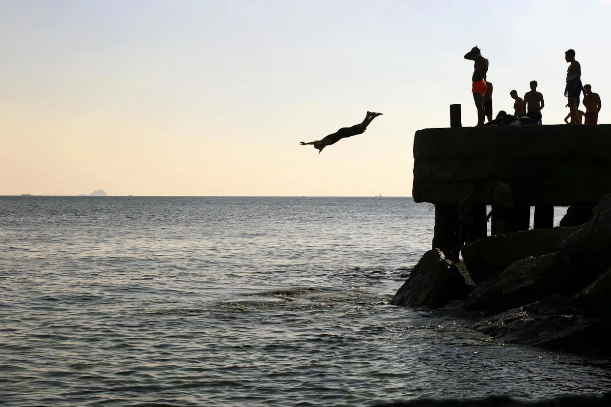 Gruppo che si tuffa al tramonto da molo a Istanbul, svago sul mare