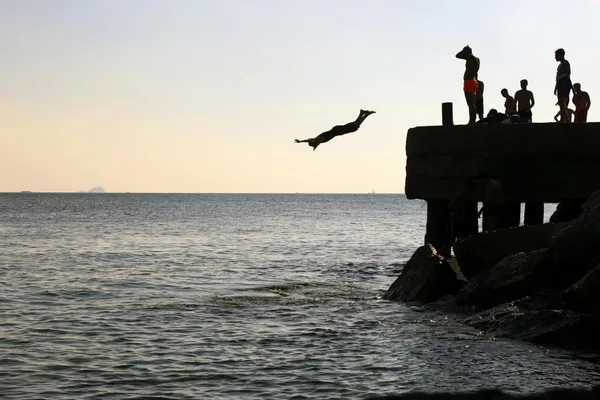 Group enjoying a sunset dive from a concrete pier in Istanbul, capturing leisure and recreation by the sea.
