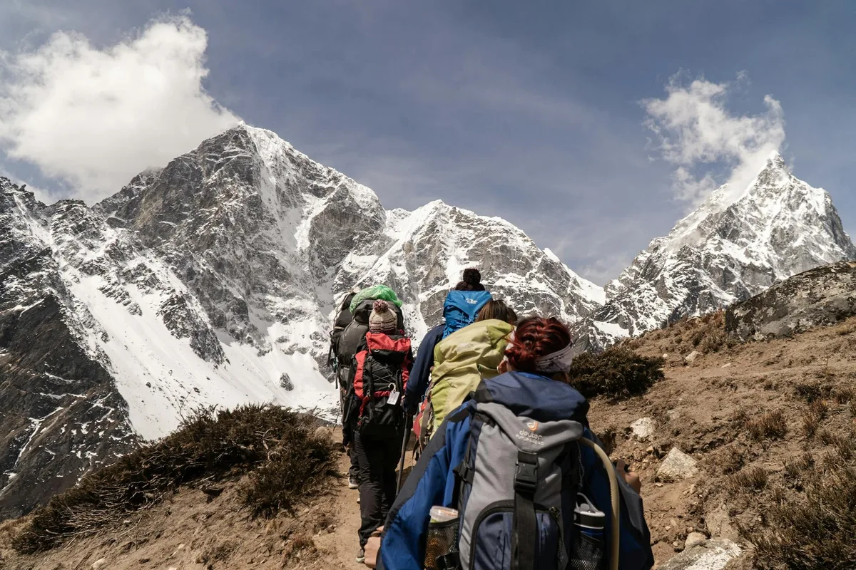 Wandergruppe bei sonnigem Wetter mit schneebedeckten Bergen im Hintergrund