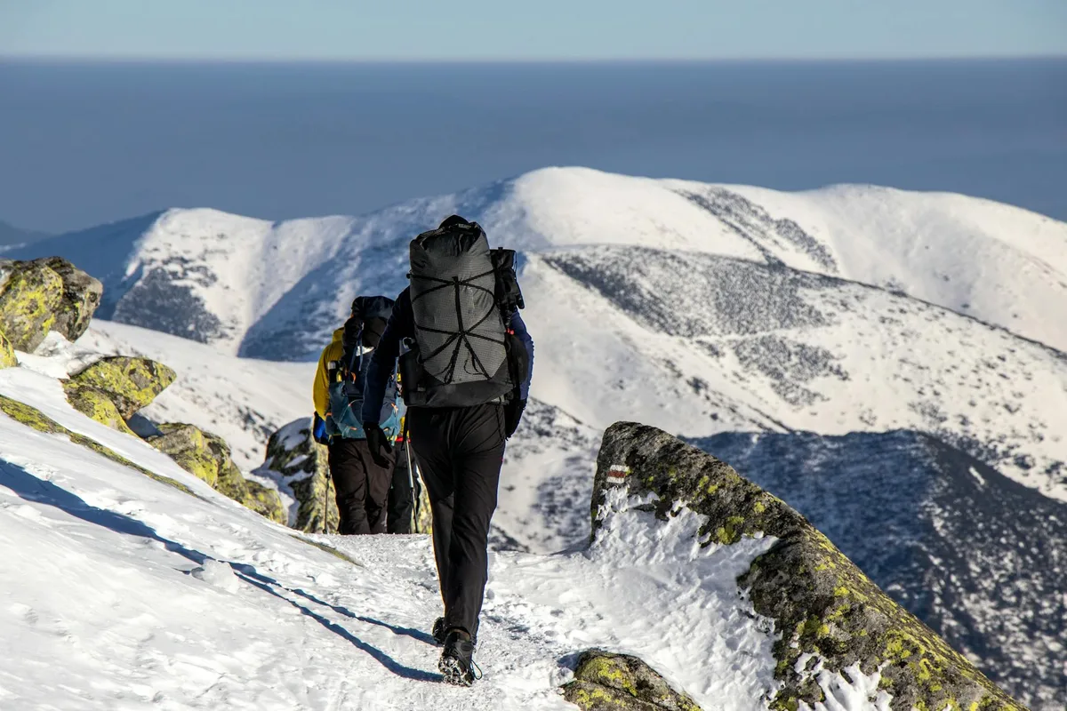 Escursionisti con zaino su montagne innevate in una giornata invernale di sole