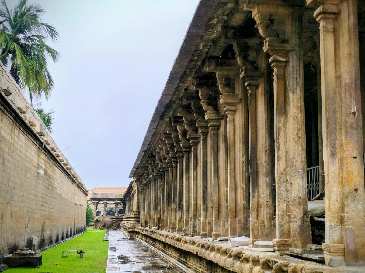Lunga fila di pilastri in pietra in un antico tempio tra verde lussureggiante