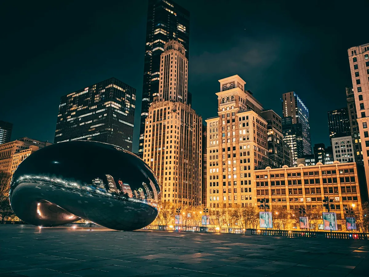 Vista notturna di Cloud Gate e grattacieli al Millennium Park di Chicago