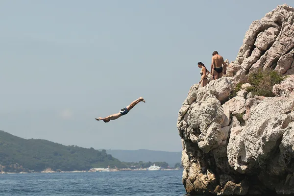 Thrilling dive from rocky cliff into the ocean on a sunny summer day.