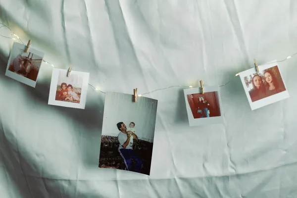 Polaroid photos hanging on a string with clips and lights evoke nostalgia and warmth.