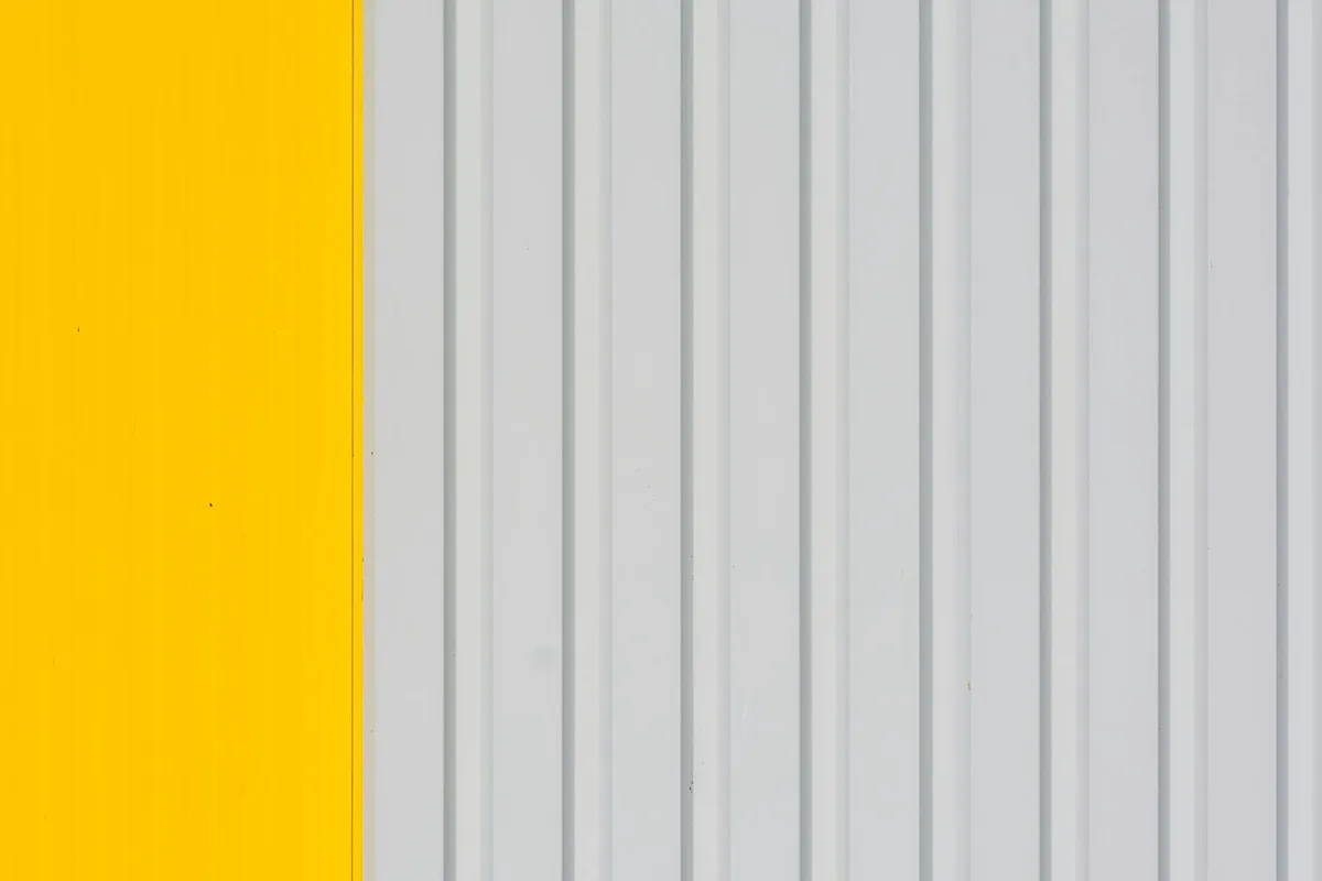 Immagine minimalista di parete a strisce gialle e bianche, ideale per sfondi e progetti di design.