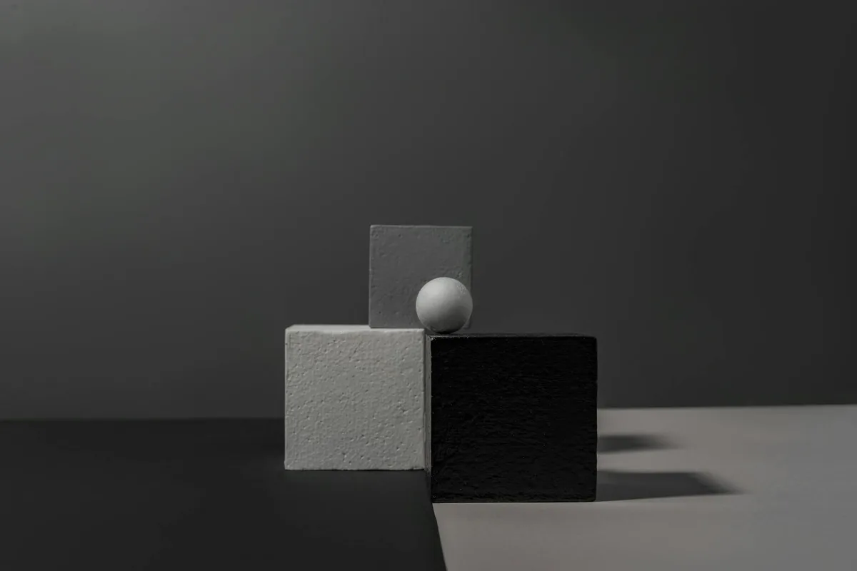 Minimalistisches Stillleben mit geometrischen Blöcken und Kugel auf kontrastierendem Hintergrund