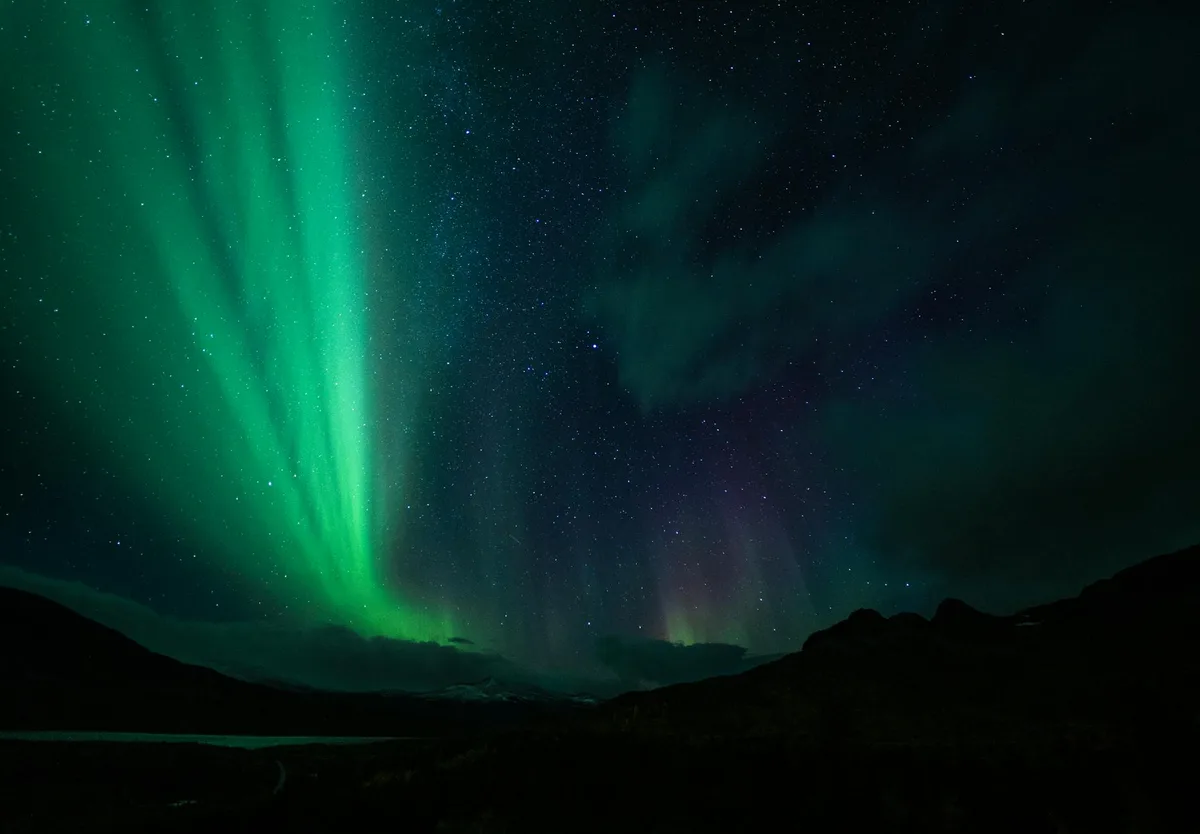Atemberaubendes Nordlicht mit leuchtenden Grün- und Lilatönen am Nachthimmel