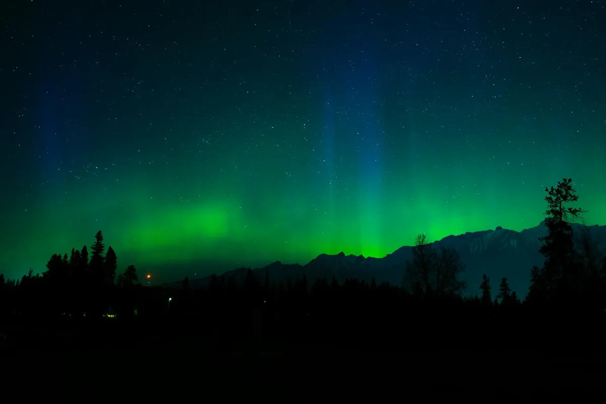 Polarlichter über einer ruhigen Berglandschaft mit sternklarem Nachthimmel