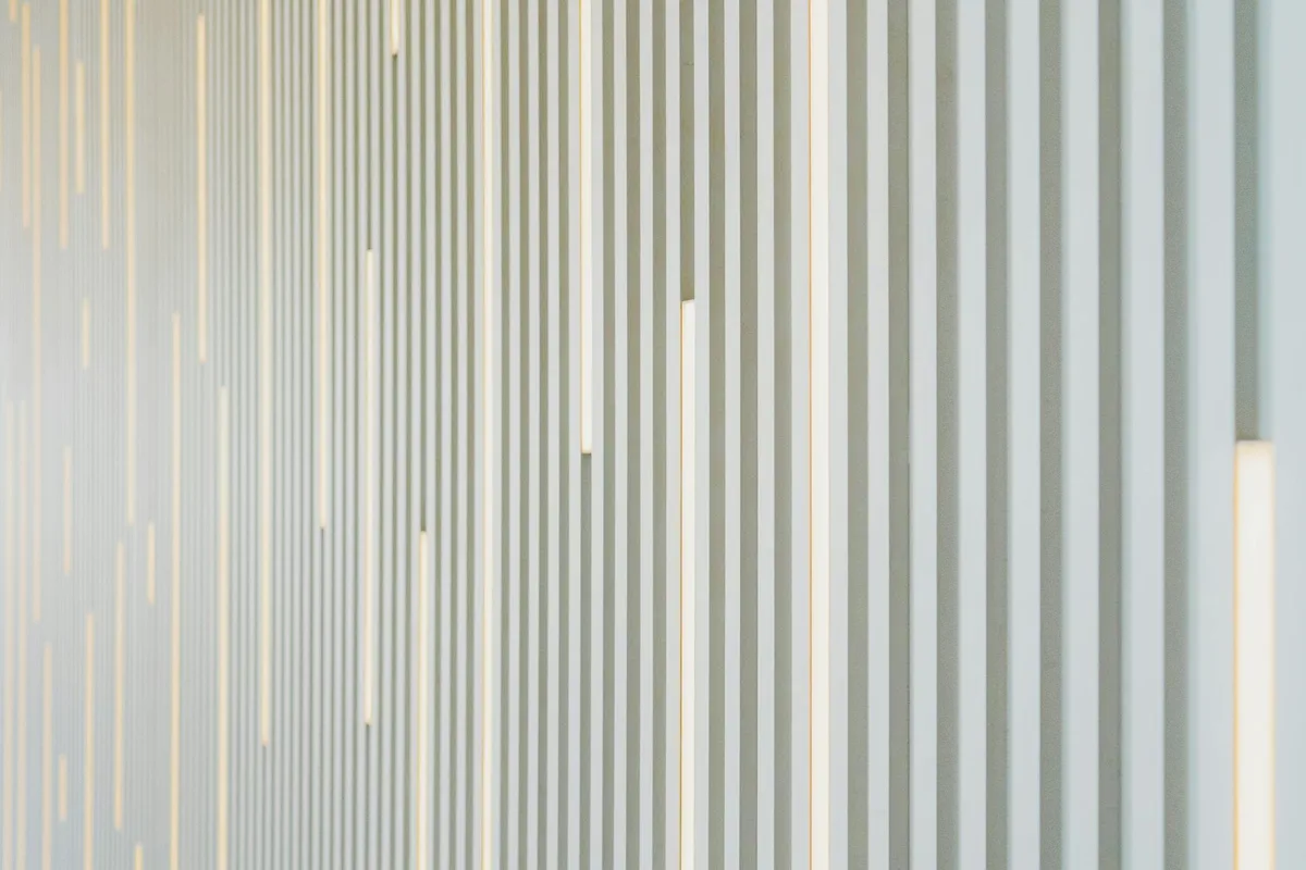 Parete bianca contemporanea con strisce verticali e linee illuminate