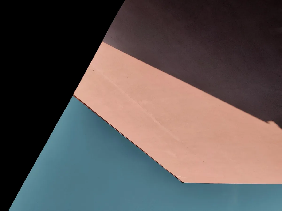 Kontrastreiches blaues und rosa Dach eines modernen Hauses mit geraden Linien und Sonnenschatten von oben